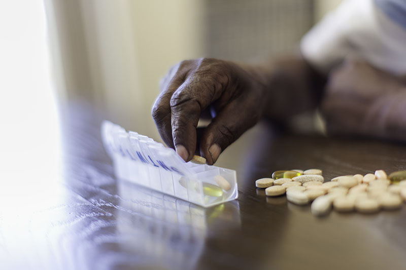 Man placing medication into a pill dispenser