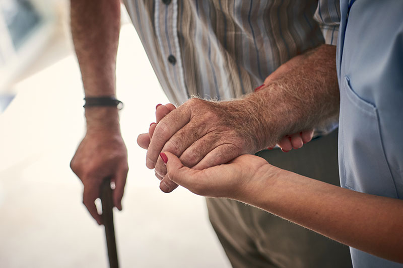 elderly man holding hands with a nurse
