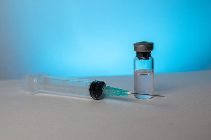 Vial of medicine and needle on a blue background